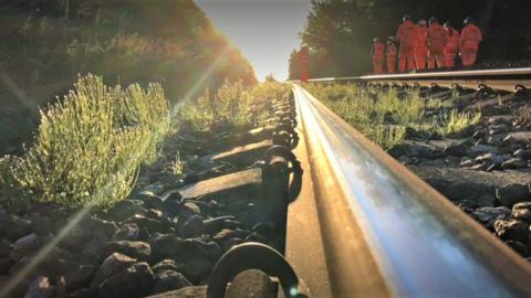 Stock image of a railway track with workers wearing hi-vis jackets
