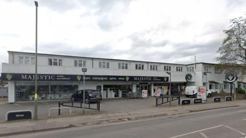 A wine shop in Molesey, Surrey. There is a black car parked outside the shop.