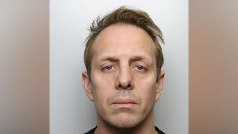 A police mugshot of Andrew Garbutt, who has short blonde receding hair and blue eyes.