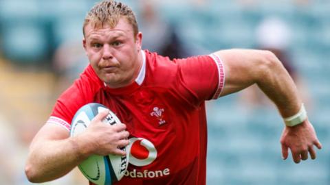 Dewi Lake in red Wales jersey runs with ball under his right arm
