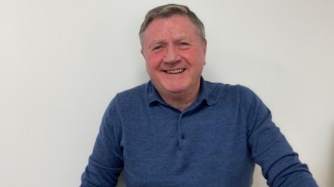 Dennis Jones wearing a blue long-sleeve T-shirt, smiling for camera.