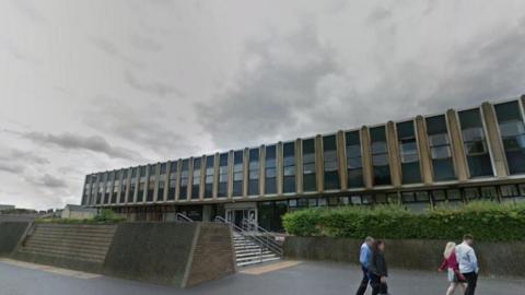 An external view of Teesside Magistrates' Court. Four people are walking past the building.