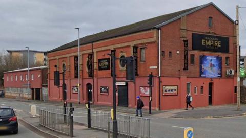 Street view image of Blackburn Empire Theatre, a large two-storey red brick building next to a road junction