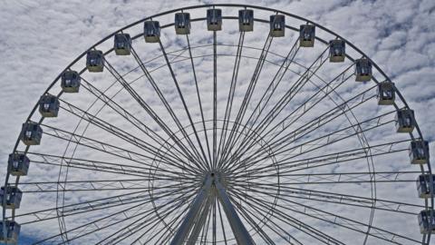 A big wheel is seen up close on a cloudly day. 