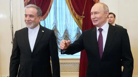Iran's foreign minister Abbas Aragchi and Putin stood next to each other, both wearing suits.