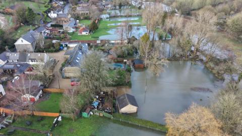 A green field with houses that have been flooded by rain water.
