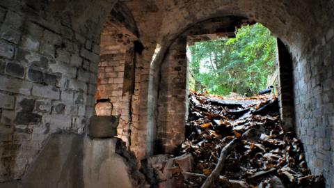 Interior shot of ice house at Deepdene Estate in Dorking showing piles of rubble by the entrance