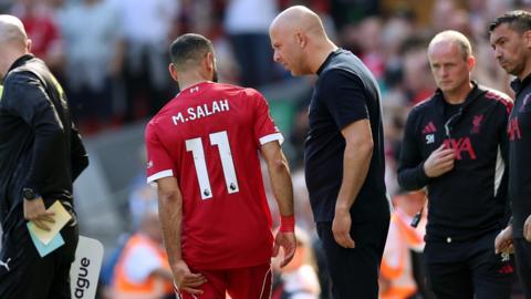 Mohamed Salah holds his hamstring talking to Arne Slot