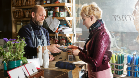 Male shop keeper serves young woman