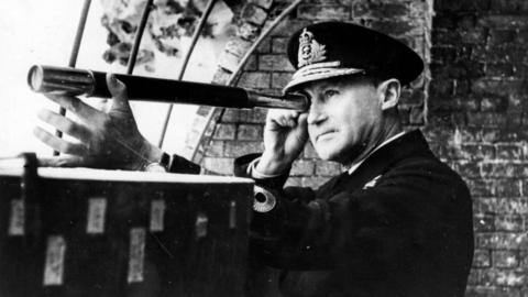 A man in a military uniform looks through a telescope. 
