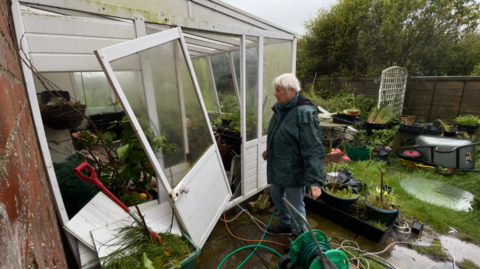 Bryony Neirop-Reading assessing damage to her sun lounge, with a window and door blown out