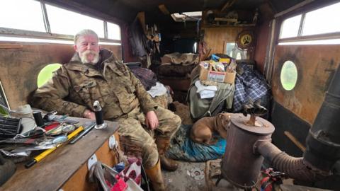 Darren "Badger" Edge sitting down in his bus accommodation. 