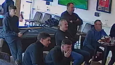 Group of men captured on CCTV watching football, with Steven Gerrard.