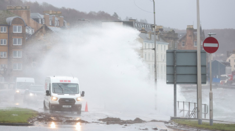 Two vans and a car being swamped with water on the front at Oban