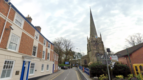 Church Walk in Hinckley is pictured. A row of terraced homes are on one side of the road and a church with large spire on the other side.
