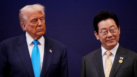 U.S. President Donald Trump smiles as he stands next to South Korean President Lee Jae Myung
