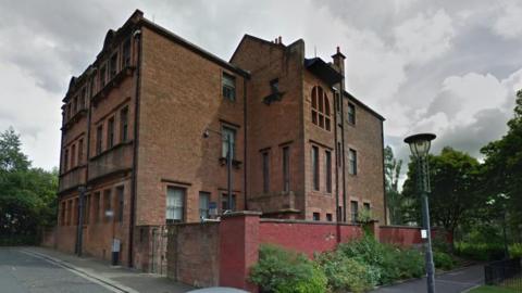 The old Martyrs' School - a red brick building with lots of windows. There is a wall around part of it and a lamppost next to it.