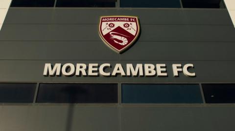 A sign with the Morecambe FC crest outside their Mazuma Stadium home