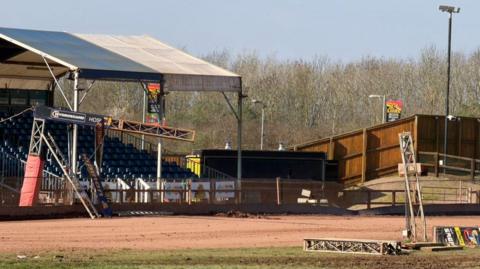 Gantry partly hanging lose and more of it on the ground of speedway track.