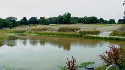 Wide shot of a pond with traffic cones around the edges