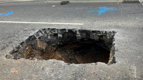 A cavernous, large square hole in a road. 