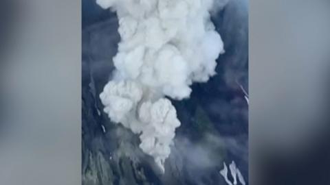 Aerial view of volcano erupting with huge plumes of white smoke