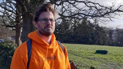 A man in glasses and an orange hoody