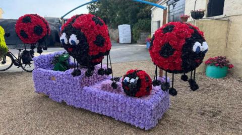 A float covered in large round ladybirds made from flowers 