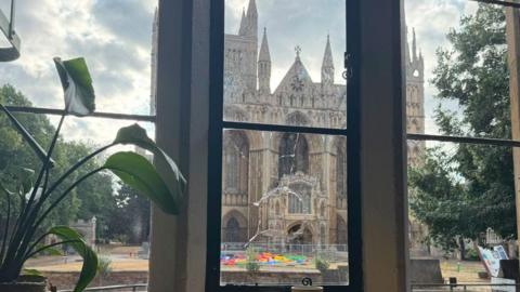 An photo taken from inside the cafe shows a smashed window looking out onto a cathedral.