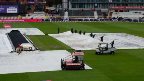 Ground staff work on the pitch at Old Trafford Cricket Ground