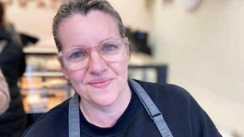 Victoria Vickery, wearing an apron and smiling at the camera in her new sandwich and cake shop in Treorchy 