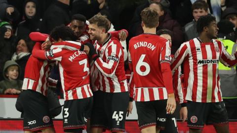 Sheffield United players hug each other in a group in celebration of a goal