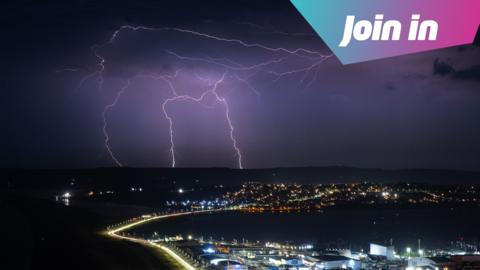 Lightning strikes are seen during a storm over Weymouth. A Join In graphic sits in the top right corner