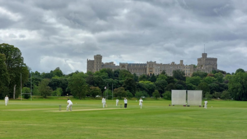 A picture of cricketers playing at the park in the shadow of Windsor Castle.