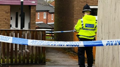 Police officer standing between police tape