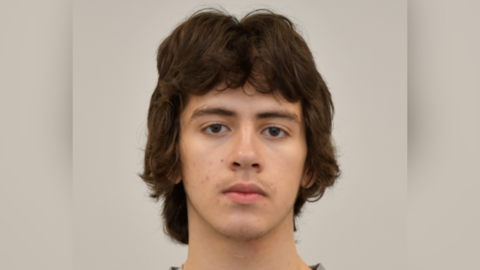 A mugshot of a teenager with long brown hair.