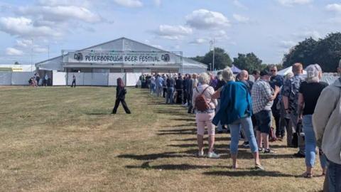 Queues of people outside a white marquee- labelled Peterborough beer festival 