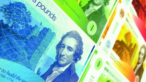 A local currency note with photos of Thomas Paine in green, orange and red