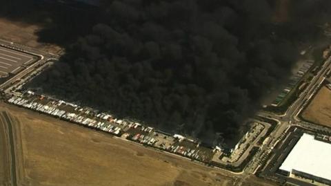 Huge plumes of black smoke rising above a field