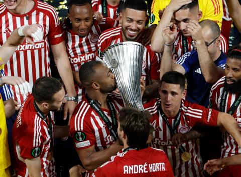 Ayoub El Kaabi kisses the trophy as Olympiakos players celebrates winning the Europa Conference League