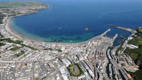 An aerial view of Douglas, which has an arching coastline and is densely populated with buildings.