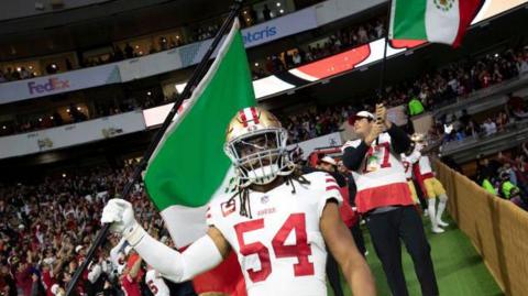 Fred Warner waves a Mexico flag before the San Francisco 49ers play the Arizona Cardinals at Estadio Azteca in November 2022