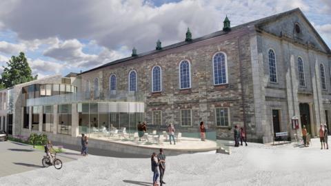 An artist impression of the extension on the Grade II listed Truro Methodist Church. The church is grey and red brick with seven arched windows along the top on the left-side of the building. Below are three square windows. At the front of the building there are three arched windows and three doors below. The extension, on the left, is glass. There is a person riding a bicycle on the left and two people looking at the extension. There are many other people walking around the church in couples or alone. 