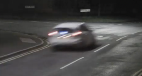 A white car driving along a road at night