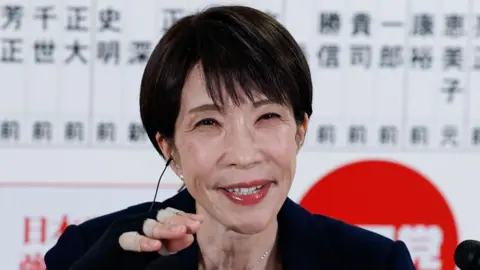 Sanae Takeuchi smiles as she addresses reporters at a press conference