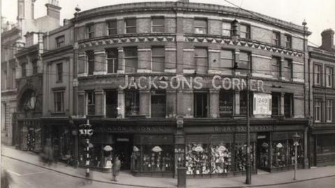 The old department store in a black and white image with the words "Jacksons Corner" on a sign going around the building