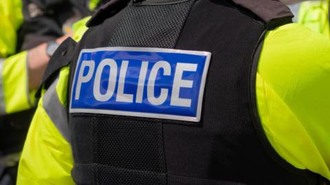 The back of a police officer's black vest. It says "POLICE" in white text on a blue background.
