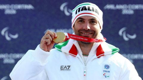 Emanuel Perathoner holds up his Paralympic gold medal on the podium