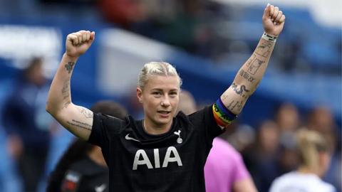 Football player in a black shirt holding her hands up in celebration