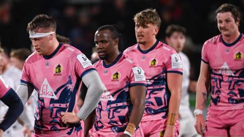 Exeter players leave the field looking dejected